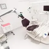 Nowoczesny gabinet stomatologiczny z fotelem, mikroskopem i sprzętem.