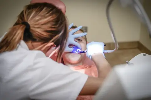 Dentysta leczy zęby dziecka w gabinecie stomatologicznym.