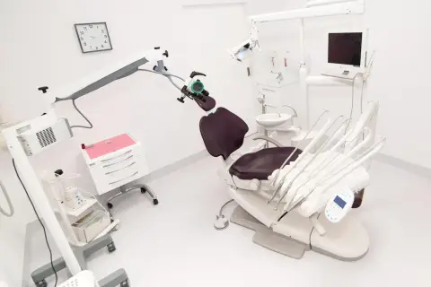 Nowoczesny gabinet stomatologiczny z fotelem, mikroskopem i sprzętem.